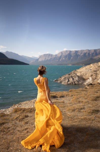 a woman in a yellow dress by a body of water